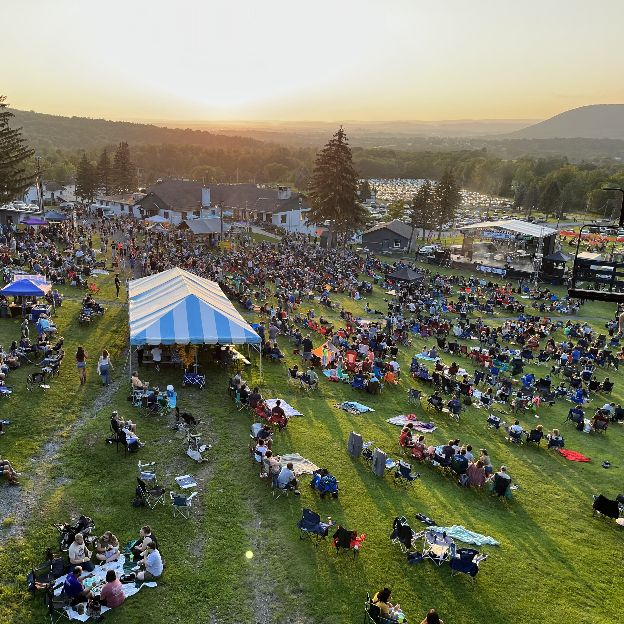 Aerial view of WingFest tent at sunset surrounded by people and Mount Nittany in the background
